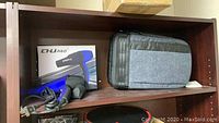 Shelf with CHU Pro blow dryer in open box, KF Concept camera backpack next to it.
