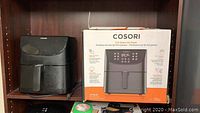 Cosori air fryer with original box showing model CP158AF 5.8-quart capacity and product features on shelf.