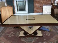 Angled side view showing distinctive geometric Art Deco base with triangular and circular elements in contrasting wood tones.