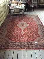Full view of the wool area rug showing overall size, color, and pattern in place on wood floor with surrounding furniture.