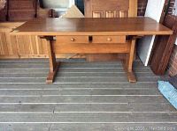 Full front view of pine table showing overall shape and drawers beneath tabletop.