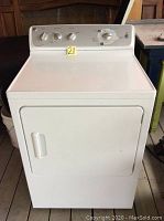 Front view of white General Electric clothes dryer showing front door with handle and upper control panel with knobs