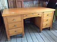 Front view of solid oak bankers desk with pedestals, drawers, brass-capped feet.