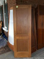 Photo of the stained wood side of the solid wooden two-pane door showing medium brown finish with two rectangular panels and aged appearance.