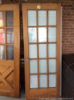 Full view of wooden French door with several glass panels, showing one glass panel missing.