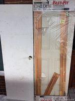 Photo showing new wooden door frame unit in original packaging labeled 'Fast-Fit' alongside a used white painted wooden door with door handles.