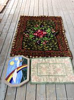 Overall view of two small rugs laying flat alongside hexagonal mosaic plaque with sticker number 33 on it.