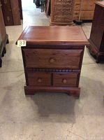 Front view of the pine wood night table showing three drawers with wooden knobs and carved details along the base.