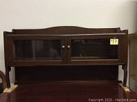 Front view of the two door display wall mount cabinet showing dark wood finish and glass panel doors with metal knobs.