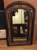 Front view of the arch top wrought iron framed mirror showing the shape and decorative circles on the frame.