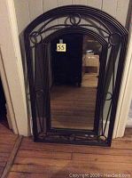 Front view of arch top wrought iron framed mirror showing full frame design and glass.