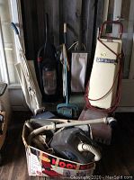 Photo showing six vacuum machines of different colors and types including one Hoover Carpetmaster