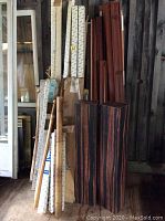Blinds and plant stands stacked vertically against a wall showing the variety and materials