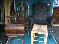 Front view of four items: black upholstered office chair, Windsor chair, woven seat stool, and Singer wooden sewing machine cover all placed together