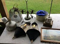 Overview of vintage and retro lighting items and decorative pieces on a table outdoors.