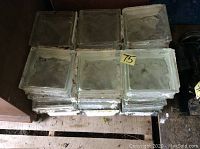 Stack of 24 clear glass blocks showing wavy texture inside and some residue on edges.