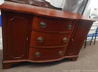Front view of the solid wood chest showing three central drawers with metal handles and two side cabinet doors closed.
