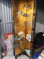Front angle of screen panels showing cranes, birds, bamboo and lotus on gold background within black lacquered frames.