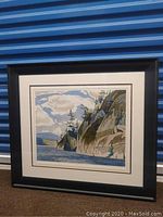 Framed landscape print by A J Casson propped against blue storage unit