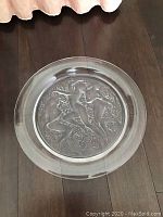 Overhead view of charger on dark wood floor showing full relief design and polished rim