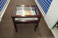 Wooden glass-top display table showing arrangement of all five ashtrays