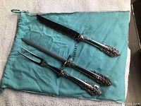 Three-piece carving set on Tiffany blue pouch showing knife, fork, sharpening steel and ornate handles