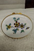 Oval white ceramic box with hand-painted multicolor floral design and gold metal trim