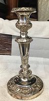 Single silver candlestick with ornate floral detailing on stem and base