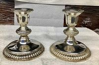 Pair of silver plated candlesticks on white cloth background showing height and design