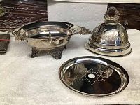 Three-part silver butter dish with separate base, dome lid, and perforated ice divider plate displayed on white towel.