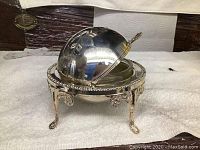 Front view of the butter dish with dome lid partially open showing lid engravings and base details