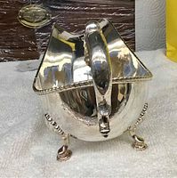 Front view of silver plated gravy boat showing overall shape, feet and edging