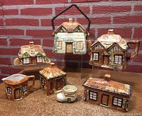 Overview photo showing all ceramic cottageware items in the lot arranged on a table with brick background.