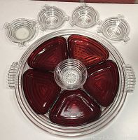Overall set display of clear Manhattan Ribbed relish tray with five ruby red inserts and clear round center insert, plus four clear Manhattan Ribbed ash trays above