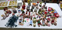 Overview of numerous Christmas tree ornaments and miniature village figures spread on a table.