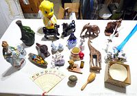 Top view of all items on a table including pig bank, wood animals, Lenox pieces, fan and other knickknacks