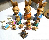 Top view of the full set of vintage composite bunny family figurines showing the three large adult bunnies and assorted smaller bunnies arranged on a table.