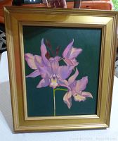 Frontal view of the framed oil painting "Shadows on Cattleya" showing pink and purple orchid flowers against dark green background.