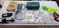 Photo of entire fishing lot on table, including rods, hooks/lures, books, net, and tackle box