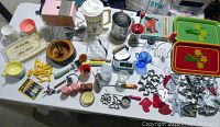 Full view of vintage kitchen items laid out on table including electric can opener, trays, cookie cutters, corn cob holders, and various kitchen gadgets.