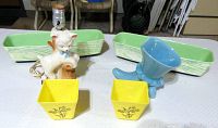 Front view of all items arranged on table showing 2 green Shawnee window boxes, yellow square planters, blue boot lamp, and white cat lamp