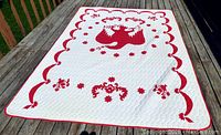 Full view of vintage red and white eagle quilt laid out flat showing overall design and condition.