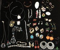 Full view of assorted jewelry and religious medals on black surface