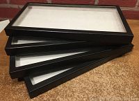 Stack of four black-trimmed rectangular display cases with glass tops, showing front and side profile, detailing size and condition.