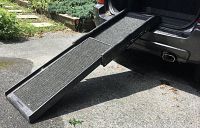 The retractable dog ramp extended from the back of an SUV, showing the ramp's length and carpeted surface for traction.