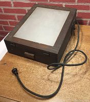 Front and top view of the dark wood rectangular light box with frosted glass panel on top and old black cord coiled beside it.