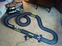 Full view of the Speed Express slot car track laid out on carpet with original box in background showing branding and image of track design