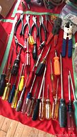 Tools displayed on red mat including screwdrivers, pliers, and wire cutters arranged side by side
