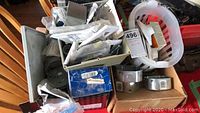 Full view of numerous electrical hardware items including boxes, plates, and straps in boxes and plastic containers.