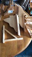 Photo showing various sizes and styles of wooden shelving brackets arranged on a wooden table, with some featuring triangular support structures and curved decorative edges.